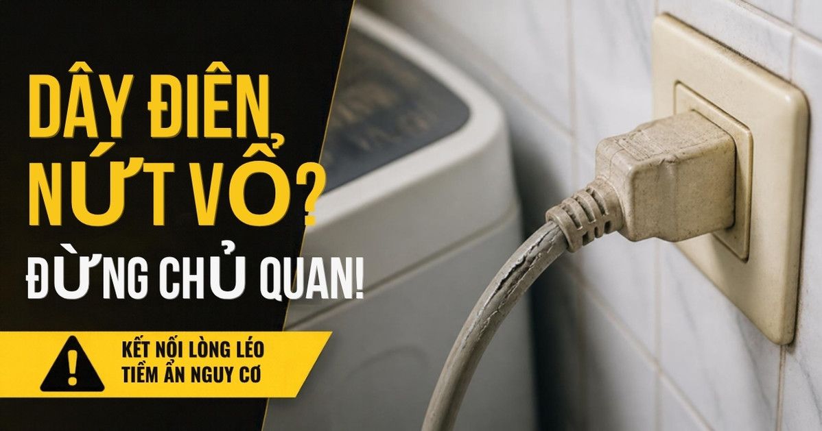 Cận cảnh phích cắm cũ ngả vàng và dây nguồn nứt vỏ cắm vào ổ điện trên tường sau máy giặt